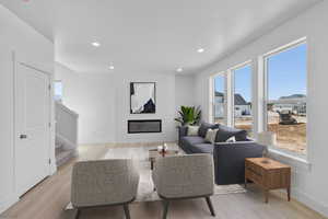 Living room with stairs, light wood-style floors, recessed lighting, and a fireplace