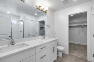 Bathroom featuring a spacious closet, a stall shower, double vanity, recessed lighting, and tile flooring