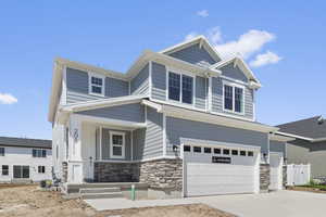 Craftsman-style house featuring stone siding, a porch, a garage, and driveway