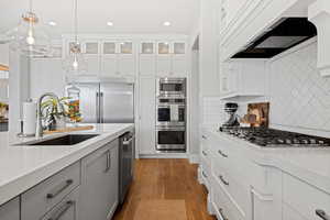 Kitchen with built in appliances, exhaust hood, light countertops, and recessed lighting