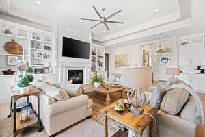 Living area featuring ceiling fan, a chandelier, a glass covered fireplace, recessed lighting, and built in features