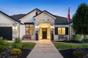 View of front of home featuring stone siding, stucco siding, a garage, and a porch