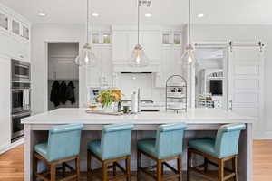 Kitchen with appliances with stainless steel finishes, backsplash, light countertops, white cabinets, and glass insert cabinets