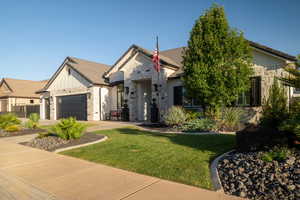 View of front of house featuring stone siding, an attached garage, and a front yard