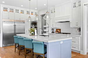 Kitchen with built in appliances, light countertops, tasteful backsplash, white cabinets, and recessed lighting