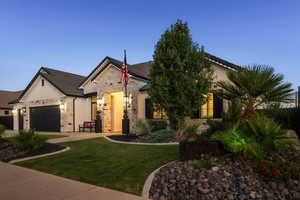 View of front of house featuring stone siding, an attached garage, a front yard, and driveway