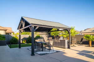 Fenced backyard with a gazebo, exterior kitchen, outdoor dining area, and a patio area