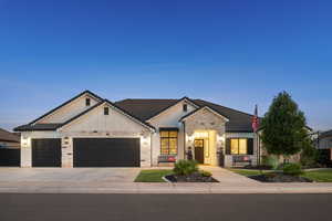 View of front facade featuring a garage, driveway, stone siding, and board and batten siding