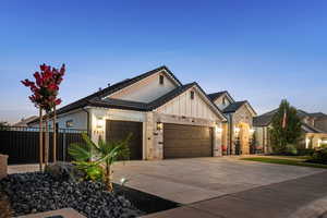 View of front of property featuring an attached garage, board and batten siding, driveway, and stone siding