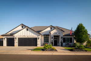 View of front of property featuring stone siding, a garage, driveway, board and batten siding, and a tile roof