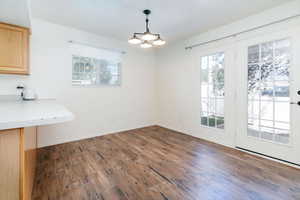 Unfurnished dining area featuring healthy amount of natural light, dark wood-style flooring, and a chandelier
