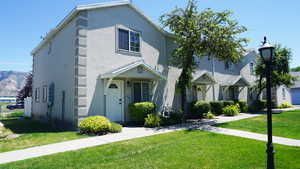Traditional townhouse with stucco siding and a front lawn. End Unit. West facing