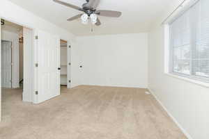 Unfurnished bedroom with light colored carpet and a ceiling fan