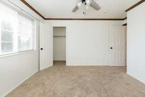 Unfurnished bedroom with crown molding, light colored carpet, and ceiling fan