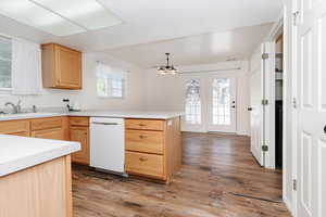 Kitchen featuring light brown cabinets, light countertops, dishwasher, light wood-type flooring, and a textured ceiling