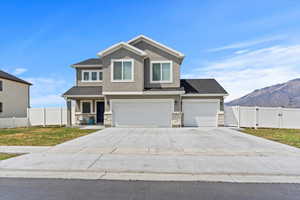 View of front facade with stone siding, stucco siding, concrete driveway, and a garage
