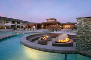 Pool at dusk featuring an outdoor fire pit, a gazebo, a community pool, and a patio area