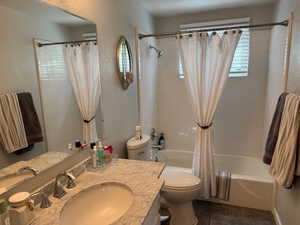 Full bathroom featuring vanity, shower / bathtub combination with curtain, tile patterned floors, and a textured wall