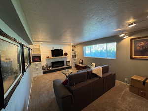 Carpeted living room with a fireplace with raised hearth and a textured ceiling