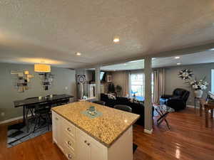 Kitchen with dark wood-style floors, a center island, a textured ceiling, white cabinetry, and open floor plan