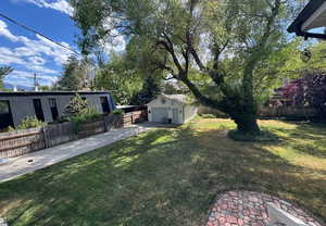 View of yard featuring concrete driveway, an outdoor structure, and a garage