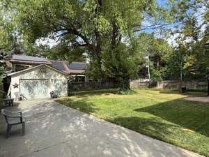 Fenced backyard featuring concrete driveway and an outbuilding