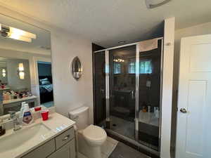 Full bathroom with ensuite bathroom, vanity, a stall shower, a textured ceiling, and tile patterned floors