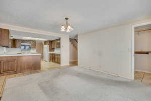 Kitchen with stainless steel microwave, light tile patterned floors, a chandelier, freestanding refrigerator, and a peninsula