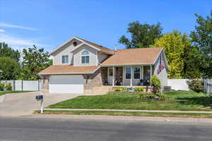 View of front of home with a garage, driveway, a porch, brick siding, and a shingled roof