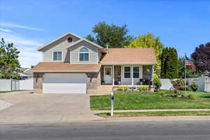 View of front of house with concrete driveway, an attached garage, covered porch, and roof with shingles