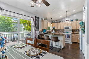 Kitchen with white appliances, tasteful backsplash, healthy amount of natural light, ceiling fan, and vaulted ceiling