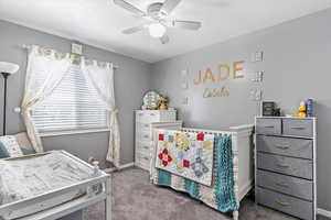 Carpeted bedroom featuring a ceiling fan and baseboards