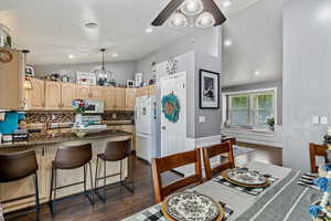 Kitchen featuring white appliances, lofted ceiling, a peninsula, ceiling fan, and tasteful backsplash