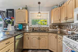 Kitchen featuring white appliances, light brown cabinets, tasteful backsplash, dark stone countertops, and hanging light fixtures