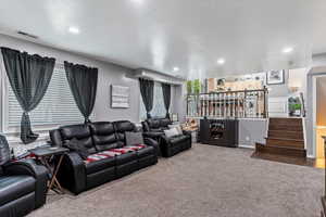 Carpeted living area featuring bar, recessed lighting, and stairway