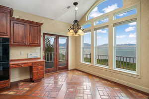 Kitchen featuring brick flooring, vaulted ceiling, a chandelier, hanging light fixtures, and a water and mountain view
