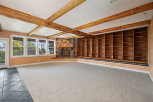 Living room with carpet flooring, beam ceiling, a fireplace, built in features, and recessed lighting