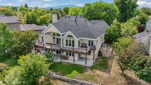 Rear view of house featuring a patio, a chimney, stucco siding, a wooden deck, and a lawn