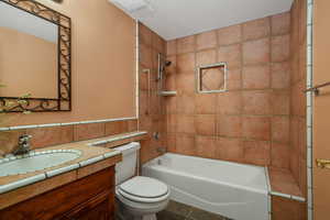 Bathroom featuring vanity, shower / bath combination, tile walls, and tile patterned floors