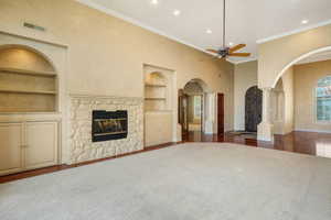 Unfurnished living room with built in shelves, arched walkways, ornate columns, a ceiling fan, and recessed lighting
