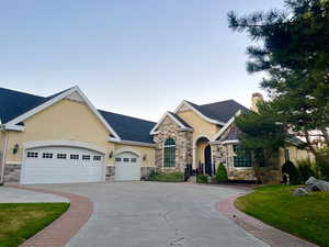 View of front of home featuring stucco siding, stone siding, concrete driveway, and an attached garage