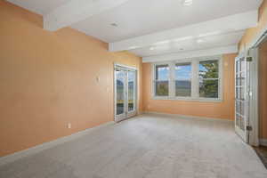Carpeted room with beam ceiling, recessed lighting, and french doors