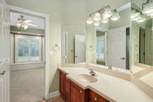 Jack and Jill bath with ceiling fan, vanity, shower, tub,and tile patterned flooring