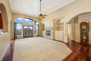 Unfurnished living room with built in shelves, ceiling fan, dark wood-style flooring, recessed lighting, and a fireplace