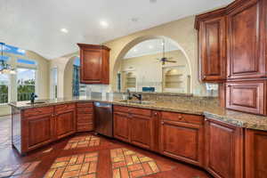 Kitchen featuring dishwasher, arched walkways, ceiling fan, a peninsula, and stone counters