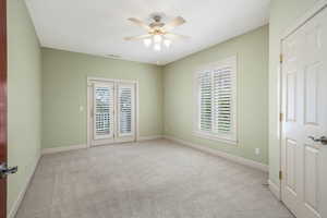 Empty room with a ceiling fan, carpet floors and french doors