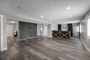 Unfurnished living room with recessed lighting, dark wood-type flooring, and a textured ceiling