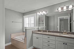 Full bathroom featuring double vanity, a bath, tiled shower, and wood finished floors