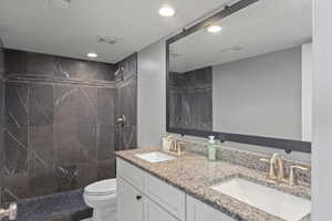 Full bathroom featuring double vanity, tiled shower, and recessed lighting