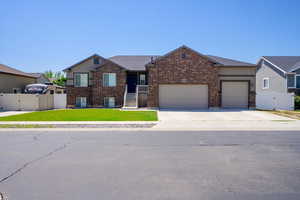 View of front of house featuring a gate, an attached garage, driveway, and brick siding